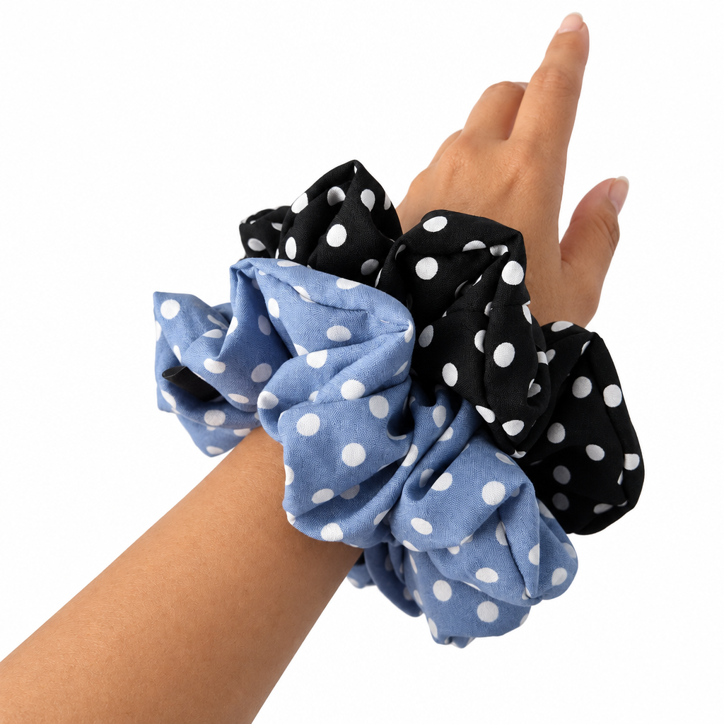 Black and blue polka-dot scrunchies worn on a wrist, pure white background