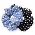 Overlapping blue and black polka-dot scrunchies on pure white