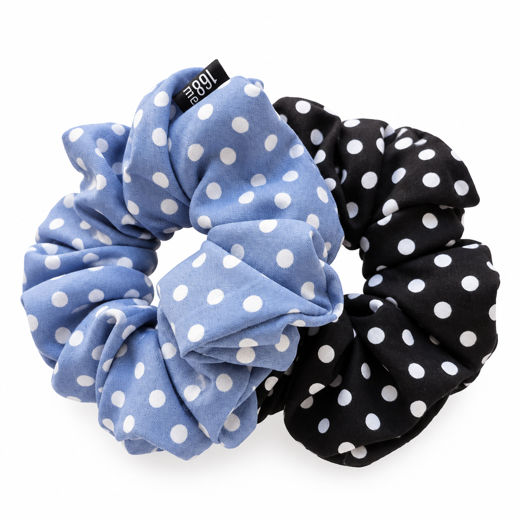 Overlapping blue and black polka-dot scrunchies on pure white